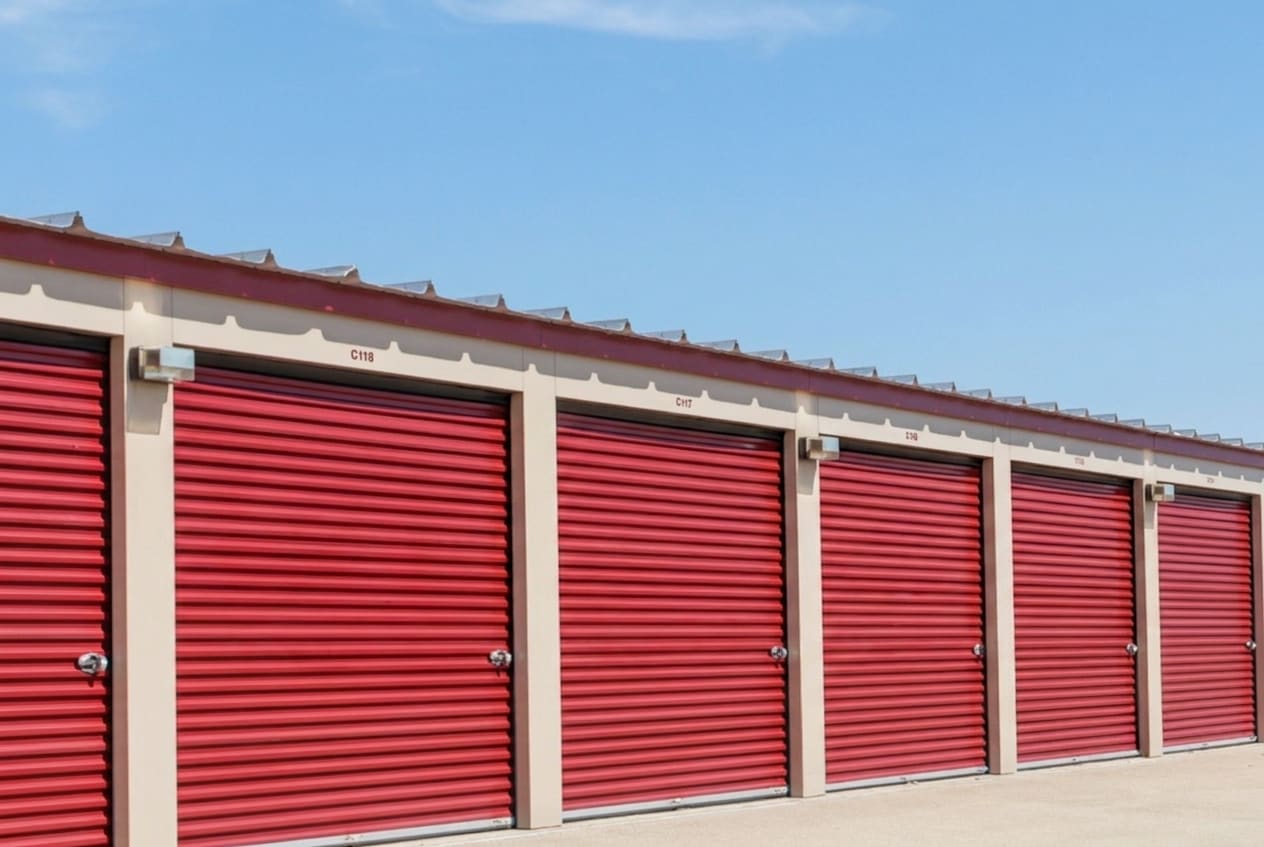 A row of red roll-up storage doors under a clear Texas sky at Superior Storage in Magnolia